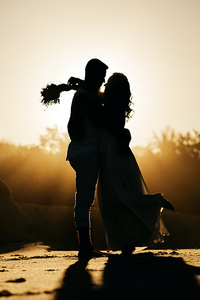 the silhouette of a married couple at sundown