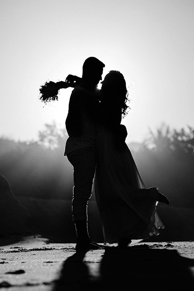 black and white picture of the silhouette of a married couple at sundown
