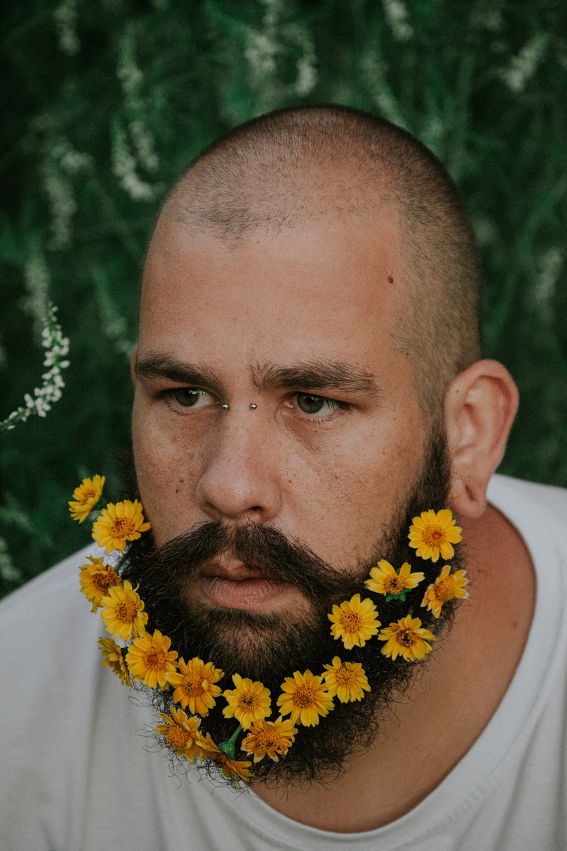a young man with his face flower-covered on his beard