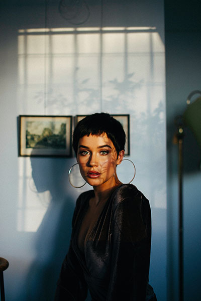 a woman with round hoop earrings in the center of a room makes an example of shadow portrait photography