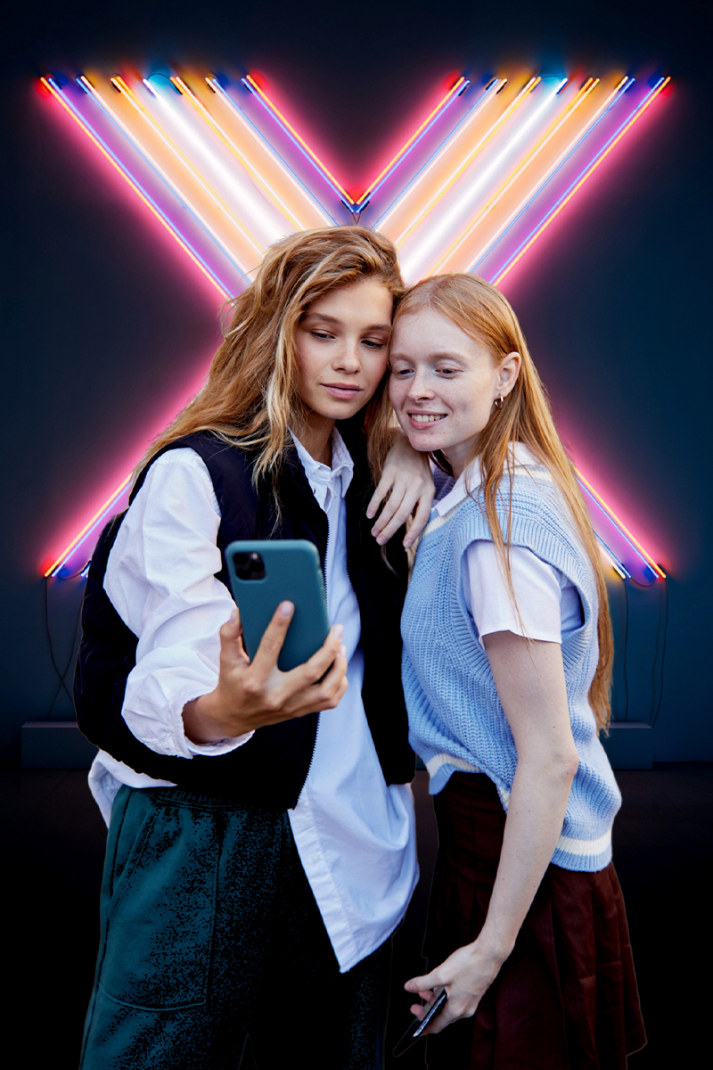 two women taking a selfie together with an X background