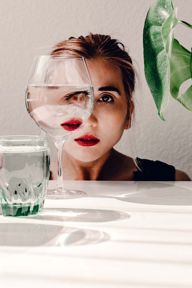 a surreal portrait of a young woman looking through the glass of water 