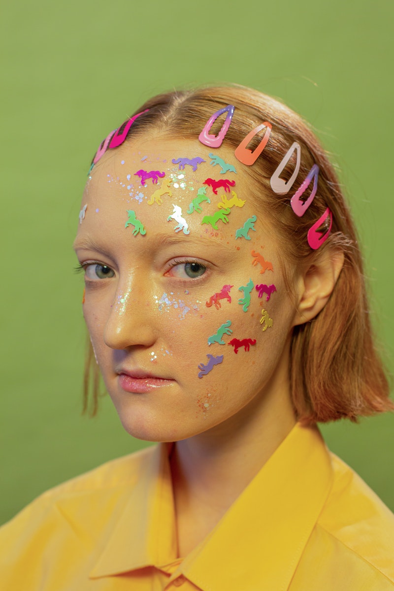 a young woman with bright glitter stickers on her face